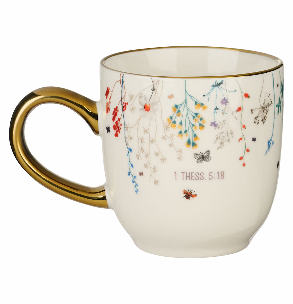 White mug with gold handle featuring floral designs and text on a white background