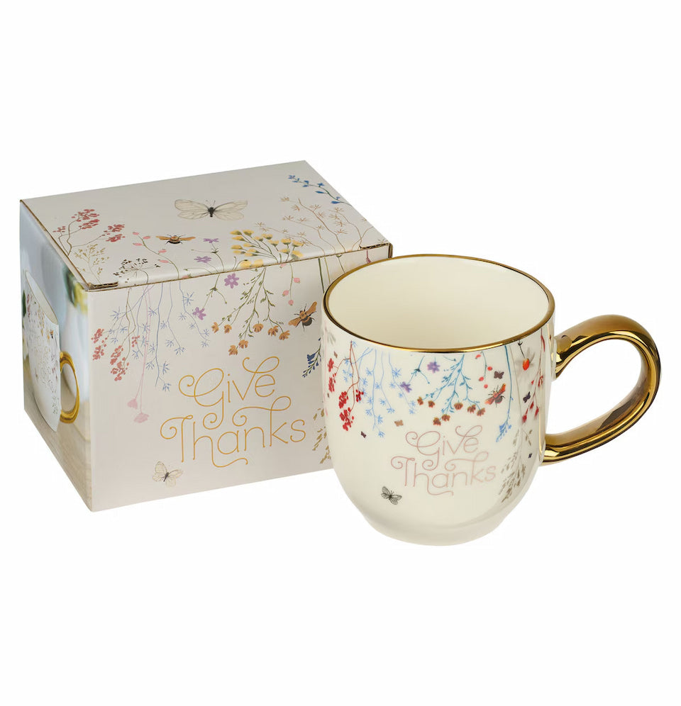 Mug with floral design and 'Give Thanks' text, accompanied by a matching box on a white background