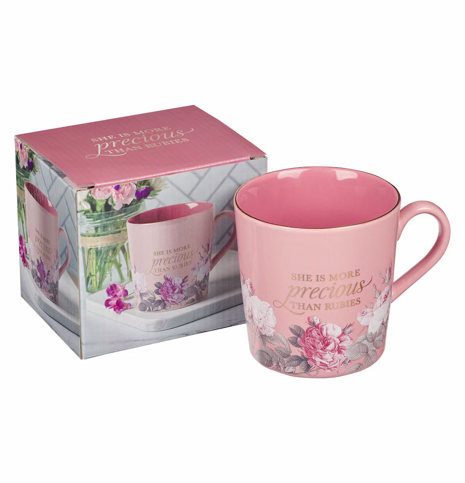 Pink mug with floral design and text, displayed with packaging on a white background
