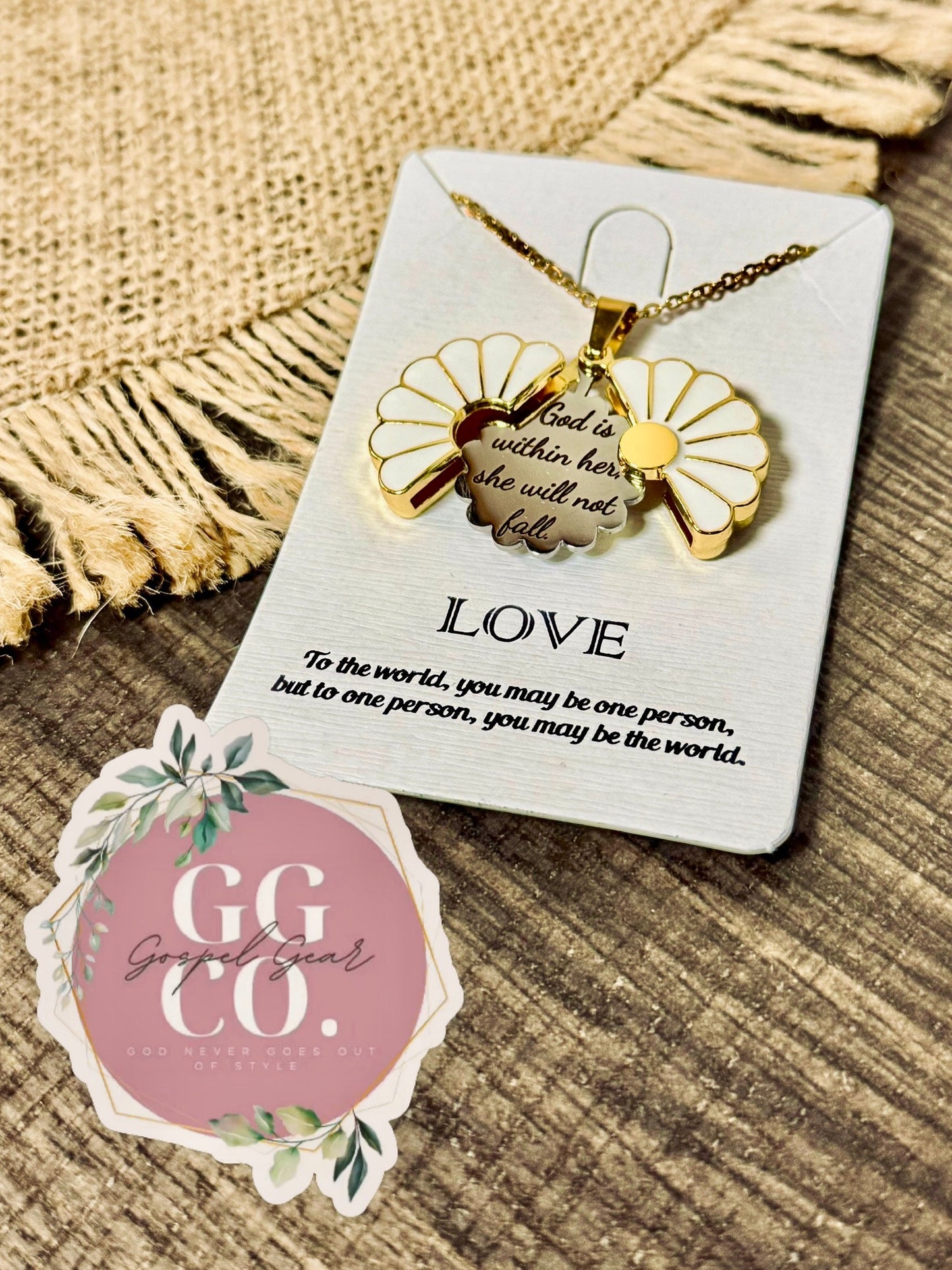 Gold necklace with a floral design on a card, placed on a textured surface with a 'GG & Co.' brand sticker.
