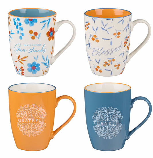 A set of four ceramic mugs in blue, orange, and white colors with floral and thankful-themed designs, including scriptural verses.