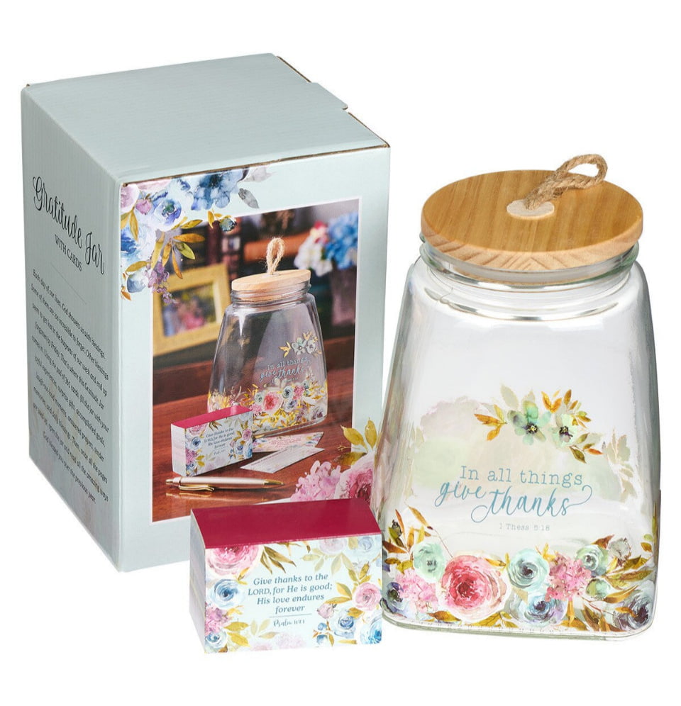 Glass jar with floral design and wooden lid next to its packaging on a white background