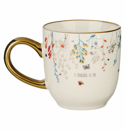 White mug with gold handle featuring floral designs and text on a white background