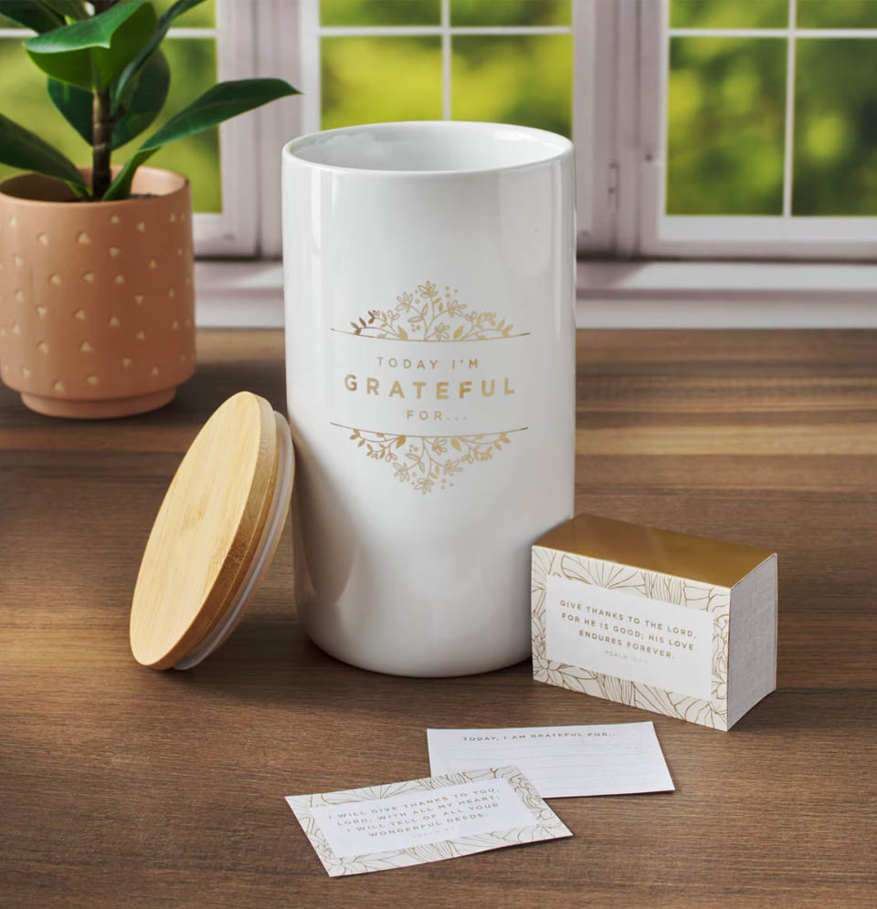 White container with a wooden lid on a wooden surface, with a plant and window in the background.