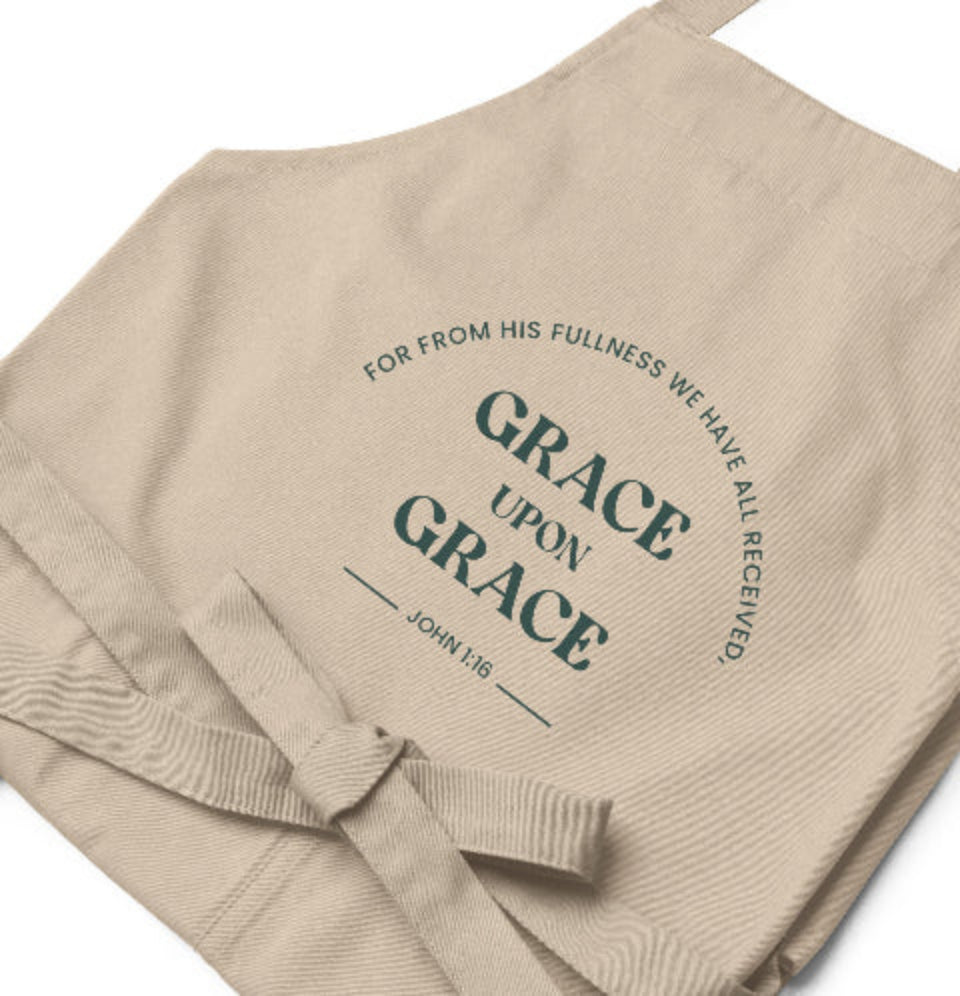 Beige apron with text 'Grace upon Grace' and 'John 1:16' printed on it.