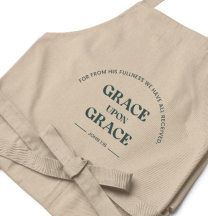 Beige apron with text 'Grace upon Grace' and 'John 1:16' printed on it.