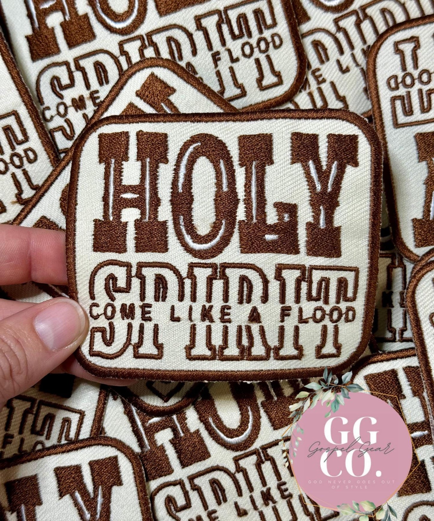 Embroidered patch with text held over a patterned background, featuring the brand 'GG CO'.